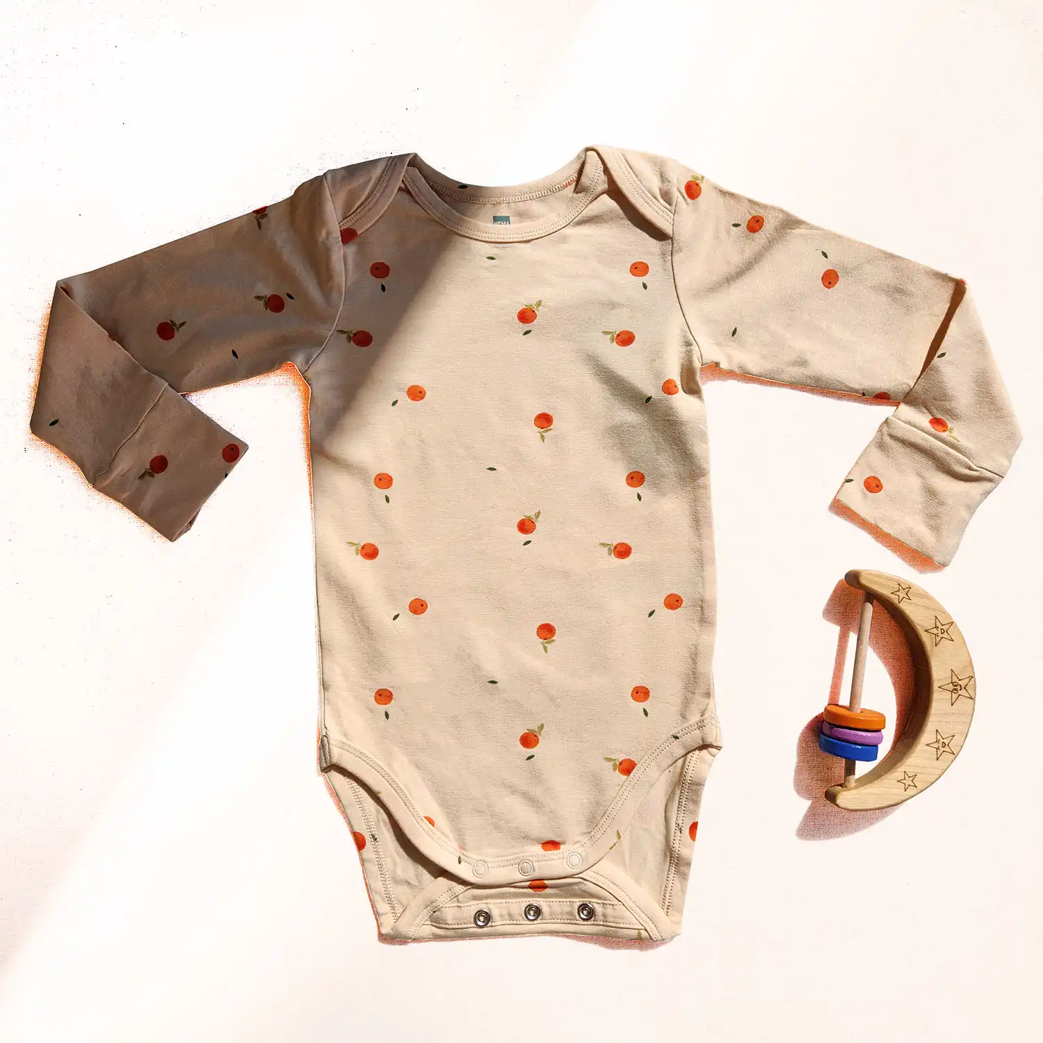 بادی آستین بلند طرح نارنگی رنگ کرم برند HEMA زیر دکمه آستین بلند طرح نارنگی رنگ کرم برند HEMA