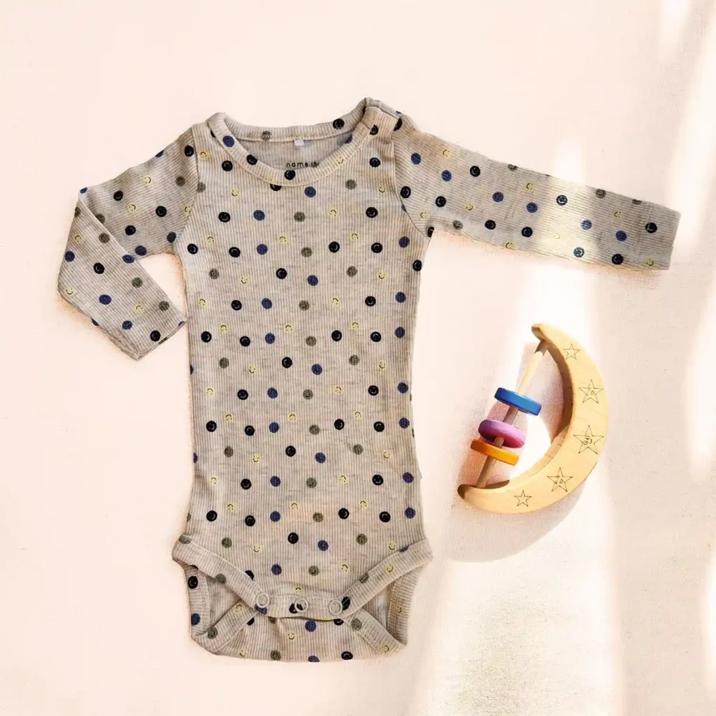 بادی آستین بلند کبریتی طرح شکلک های خندان رنگ کرم برند name it